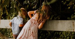 Libby Ward's children look over a fence by a green tree