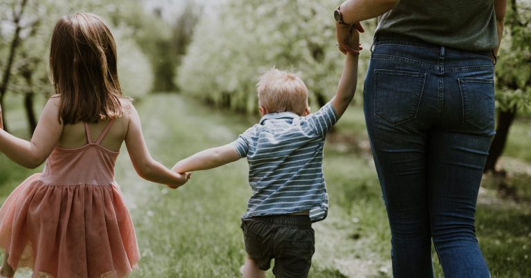Libby Ward holds the hands of her children as they walk away from the camera