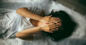 Woman laying down on bed with hands over her face